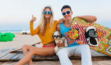 Man en vrouw zitten met hond op het strand